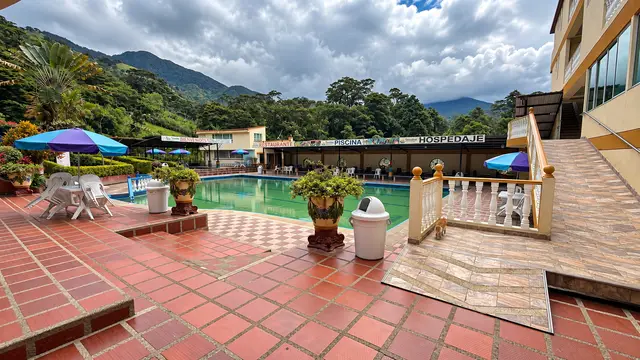 La piscina con el restaurante y el hospedaje al fondo, entre montañas